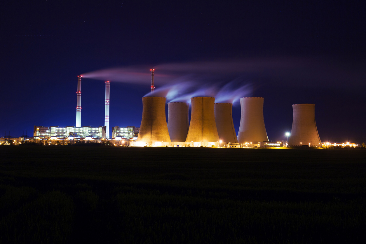 Energy production at a coal-fired power plant in the distance at night.